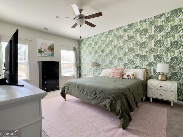 bedroom featuring light carpet, ceiling fan, visible vents, and wallpapered walls