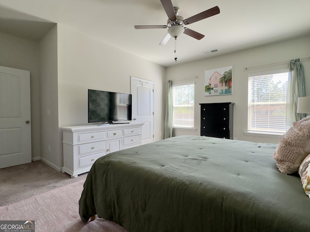 bedroom featuring baseboards, multiple windows, visible vents, and light colored carpet