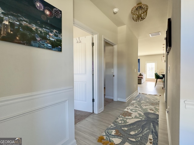 hall featuring wood finished floors and visible vents