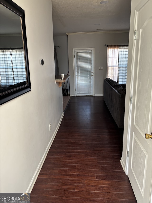 hallway featuring baseboards, ornamental molding, and wood finished floors