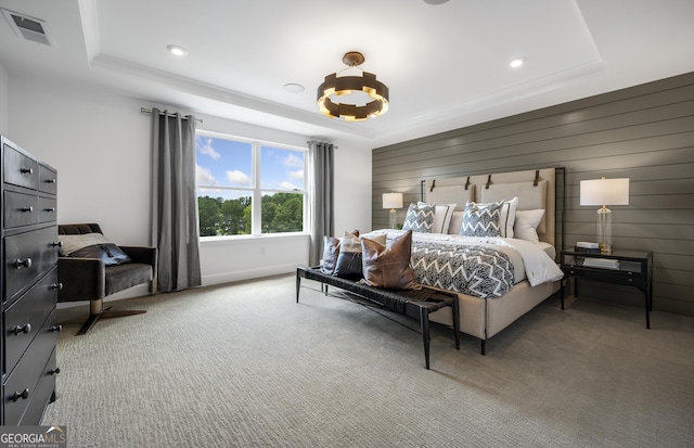 carpeted bedroom featuring a tray ceiling, visible vents, wooden walls, and recessed lighting