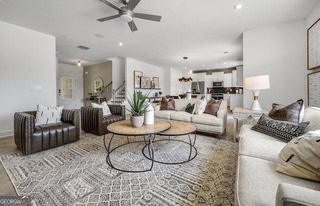 living room featuring light wood-type flooring, visible vents, stairway, and recessed lighting