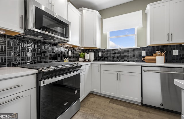 kitchen featuring stainless steel appliances, backsplash, a sink, and light countertops