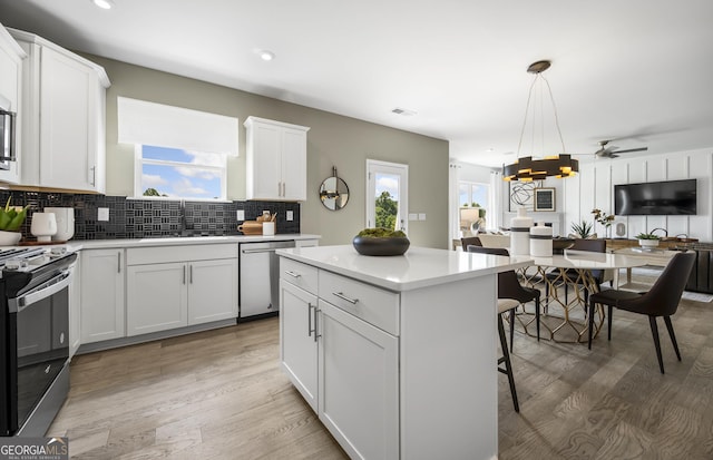 kitchen with stainless steel appliances, light countertops, decorative backsplash, a sink, and plenty of natural light