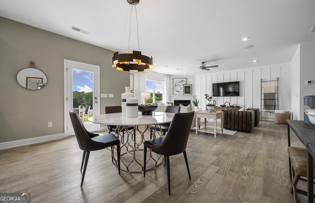 dining area featuring baseboards, a fireplace, visible vents, and wood finished floors