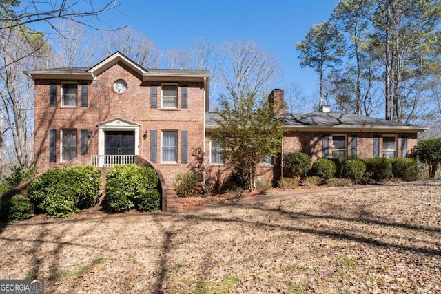 colonial house with a chimney and brick siding