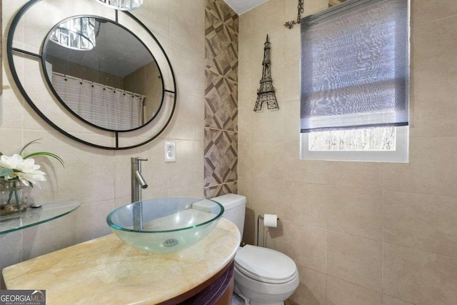 bathroom featuring toilet, tile walls, and vanity