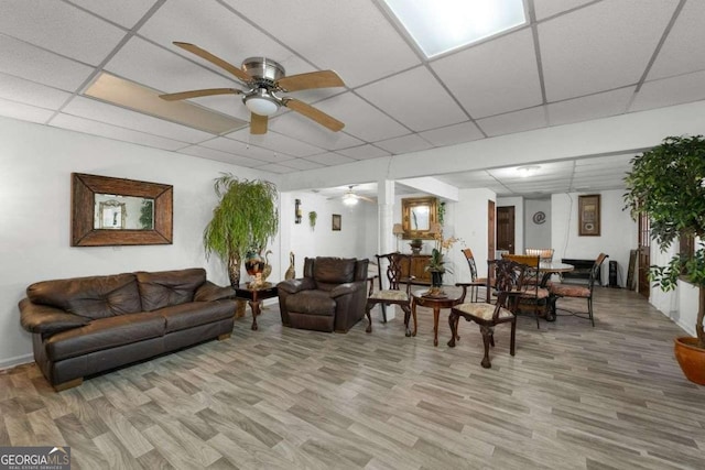 living area featuring a paneled ceiling, light wood-style flooring, and ceiling fan