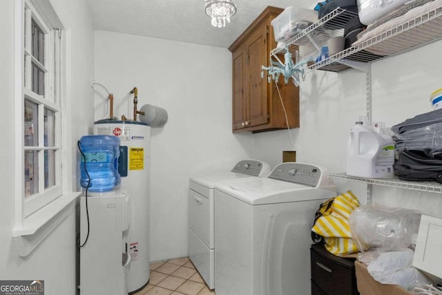 laundry area featuring cabinet space, light tile patterned floors, electric water heater, a textured ceiling, and washer and dryer