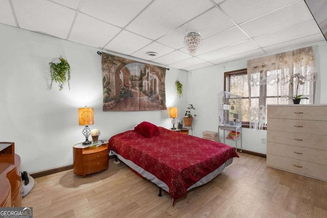 bedroom featuring a paneled ceiling, visible vents, baseboards, and wood finished floors