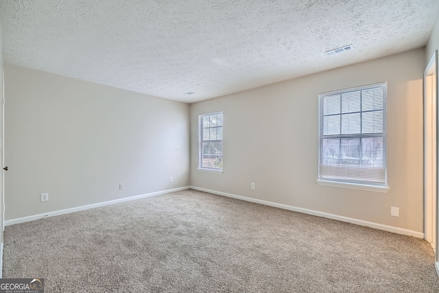 carpeted empty room with a textured ceiling, visible vents, and baseboards