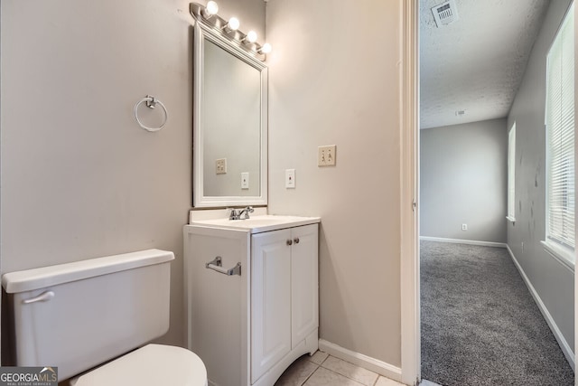 half bath featuring toilet, a textured ceiling, visible vents, and baseboards