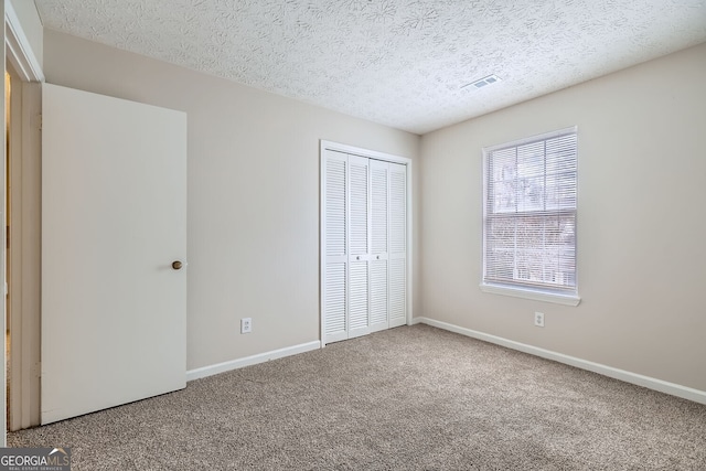 unfurnished bedroom featuring a closet, carpet flooring, visible vents, and baseboards