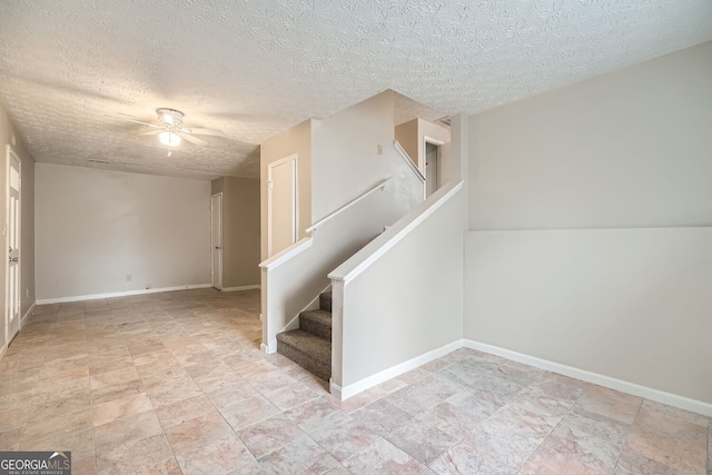 stairs featuring ceiling fan, a textured ceiling, and baseboards