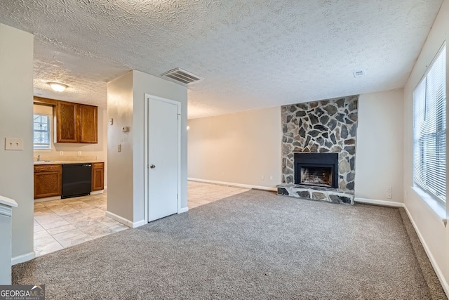 unfurnished living room featuring a fireplace, light colored carpet, visible vents, a textured ceiling, and baseboards