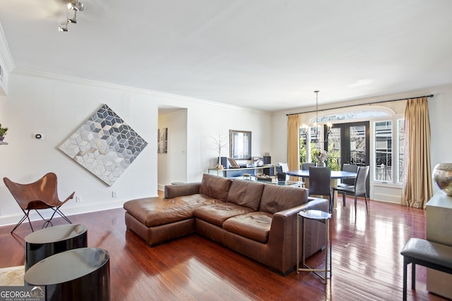 living room with baseboards, crown molding, an inviting chandelier, and hardwood / wood-style flooring