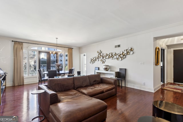 living room with crown molding, wood finished floors, visible vents, and a notable chandelier