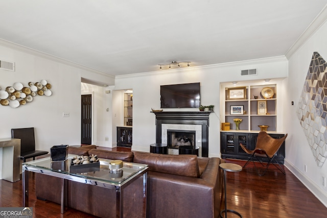 living area with a tiled fireplace, wood finished floors, visible vents, and crown molding