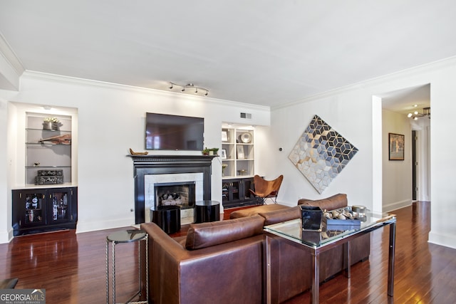 living room featuring built in features, a fireplace, ornamental molding, and wood finished floors