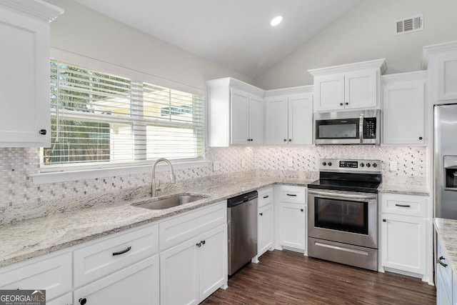 kitchen featuring appliances with stainless steel finishes, vaulted ceiling, white cabinets, and a sink