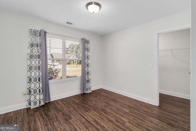 empty room featuring baseboards, visible vents, and wood finished floors