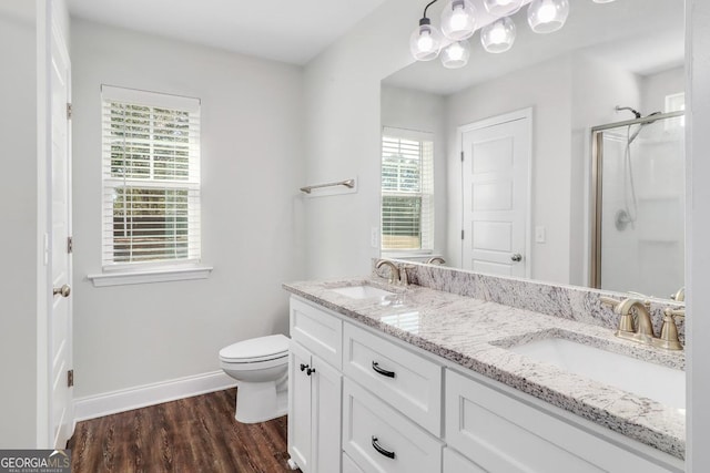 bathroom featuring toilet, a stall shower, a sink, and wood finished floors