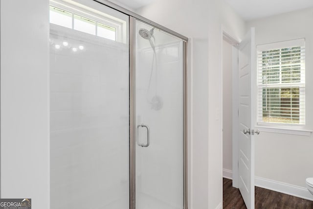 full bathroom featuring toilet, a stall shower, baseboards, and wood finished floors