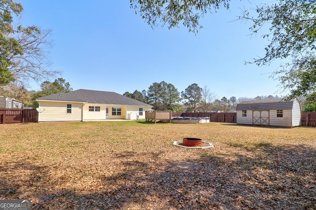 exterior space with a fire pit, a storage shed, an outdoor structure, and a fenced backyard