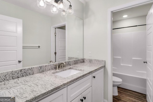 full bathroom with washtub / shower combination, vanity, wood finished floors, and toilet