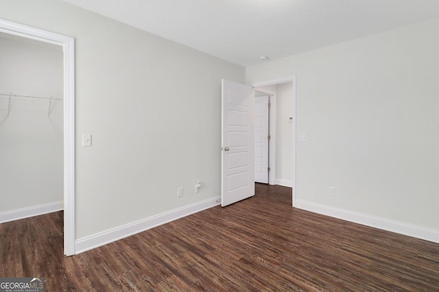 unfurnished bedroom featuring dark wood-style floors, a closet, and baseboards