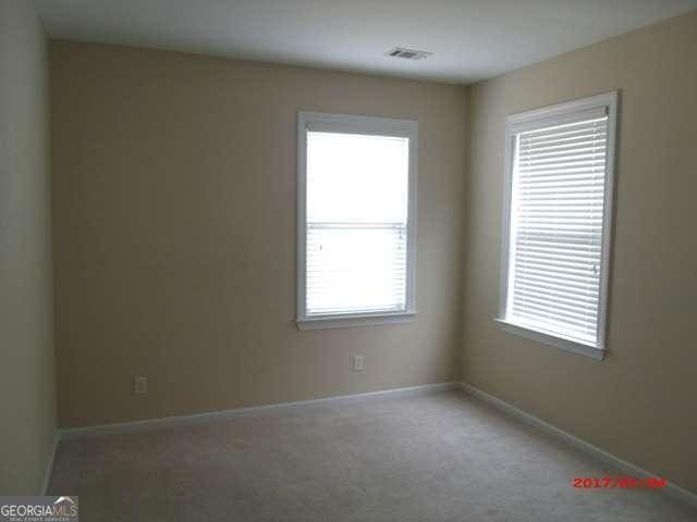 carpeted spare room with visible vents and baseboards