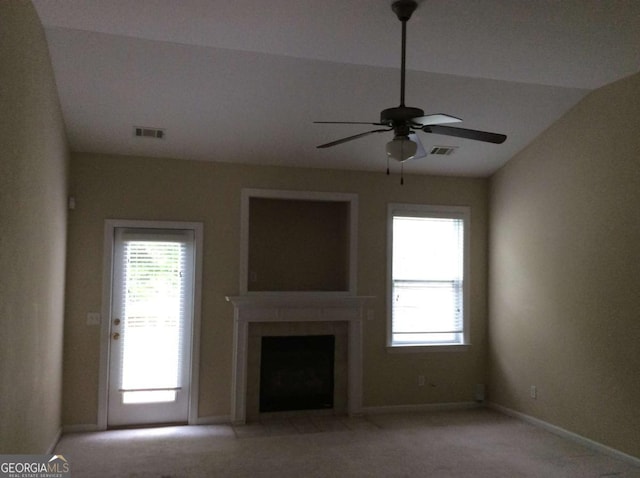 unfurnished living room with ceiling fan, a fireplace with flush hearth, visible vents, and light colored carpet