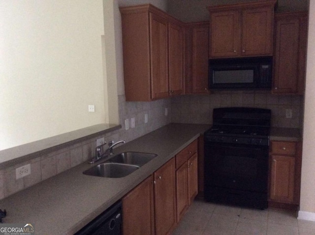 kitchen with tasteful backsplash, brown cabinetry, a sink, and black appliances