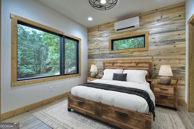 bedroom featuring wood finished floors, wooden walls, baseboards, and a wall mounted AC