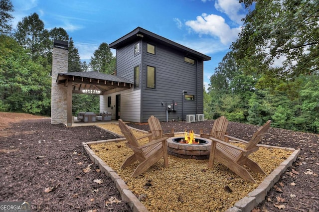 rear view of property featuring a patio, an outdoor fire pit, and a chimney