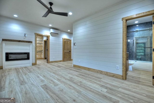 unfurnished living room with a ceiling fan, a glass covered fireplace, wood finished floors, an AC wall unit, and recessed lighting