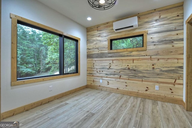 unfurnished room featuring an AC wall unit, wood walls, wood finished floors, and baseboards