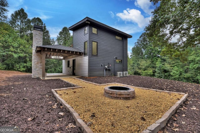 back of property with a patio area, an outdoor fire pit, and a chimney