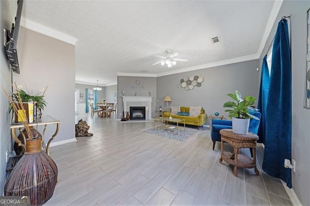 living room featuring baseboards, visible vents, crown molding, and wood finished floors