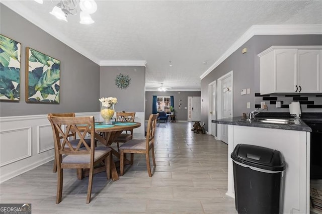 dining space with a chandelier, wainscoting, and crown molding