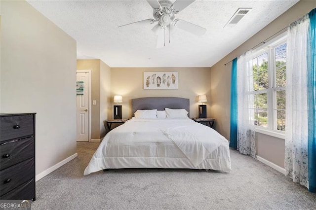 carpeted bedroom featuring visible vents, ceiling fan, a textured ceiling, and baseboards