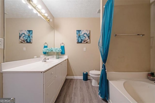 full bath featuring toilet, a bathing tub, wood finished floors, a textured ceiling, and vanity