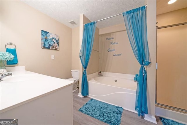 full bath featuring a textured ceiling, toilet, wood finished floors, visible vents, and vanity