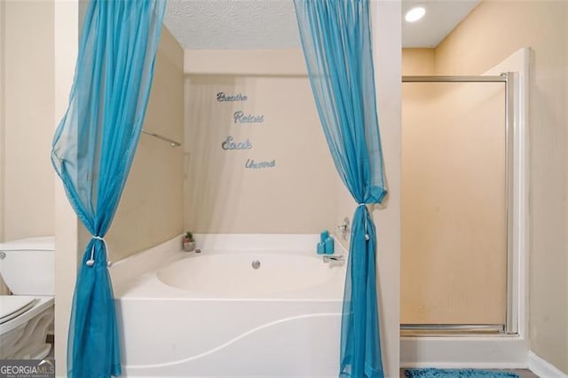 bathroom featuring a textured ceiling, a stall shower, a garden tub, and toilet