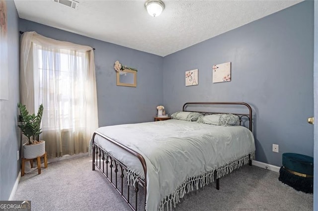 bedroom with carpet, visible vents, a textured ceiling, and baseboards