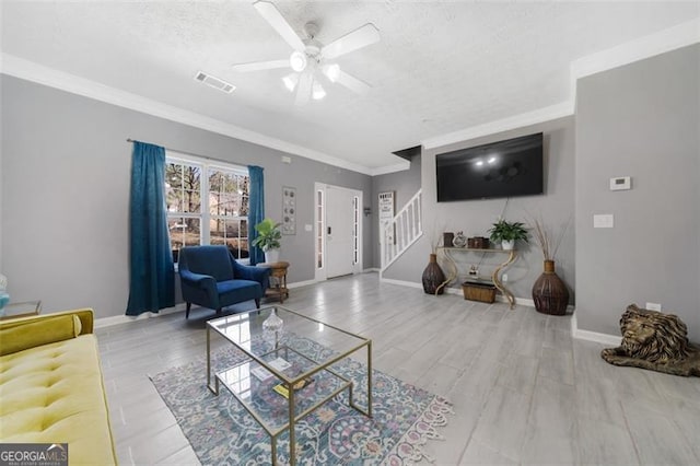 living area with visible vents, a textured ceiling, baseboards, and stairs