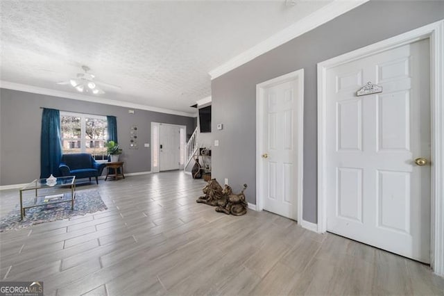 foyer with baseboards, a textured ceiling, ornamental molding, and wood finished floors