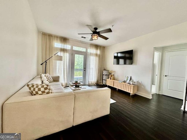 living room with dark wood-style floors, ceiling fan, visible vents, and baseboards