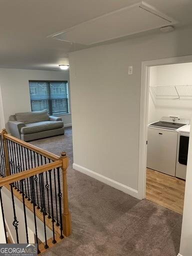 hallway featuring carpet, independent washer and dryer, an upstairs landing, and attic access