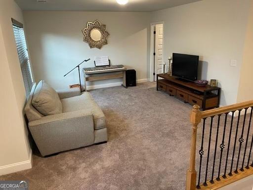 carpeted living area featuring stairs and baseboards